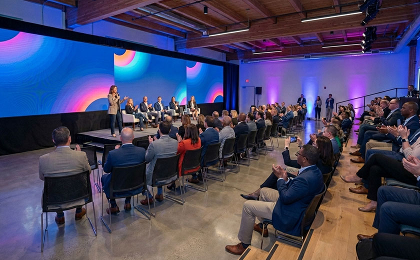 Modern corporate event space with branded stage screens and engaged audience